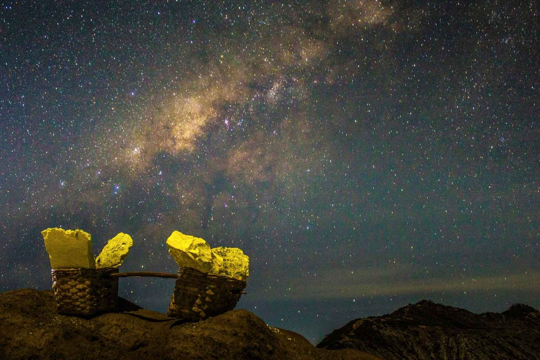 Hikers trekking Mount Ijen under starry sky at midnight