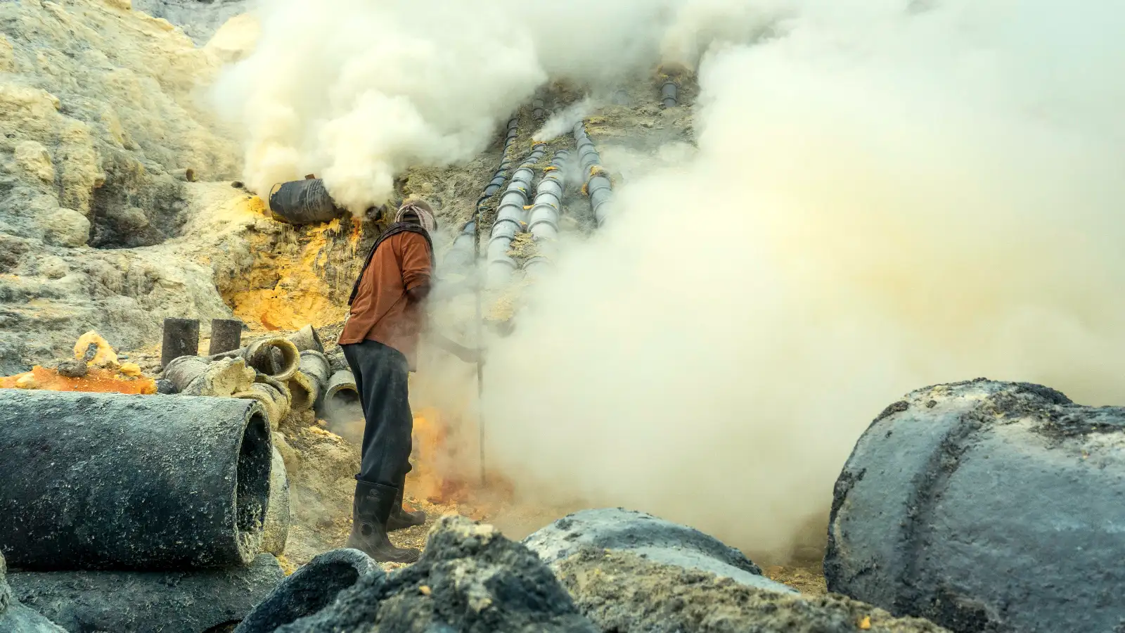 Close-up of the vibrant turquoise acid lake at Ijen Crater with yellow sulfur deposits in the foreground