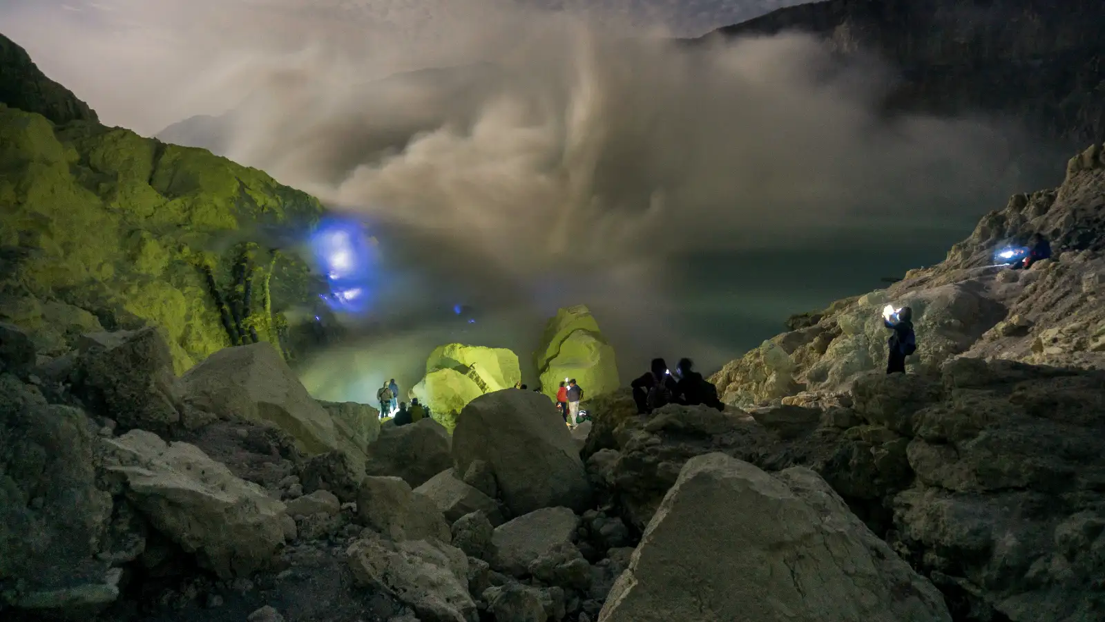 A group of hikers ascending the steep path toward the Ijen Crater rim at night