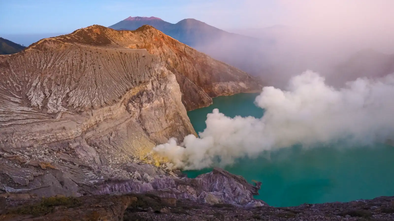Breathtaking sunrise over the turquoise acid lake of Ijen Crater