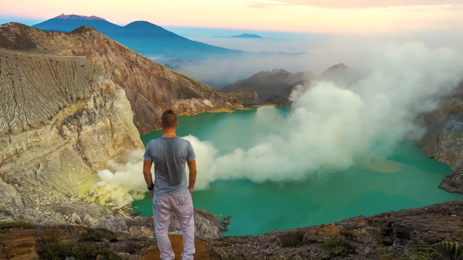 The turquoise acidic lake of Ijen Crater surrounded by yellow sulfur rocks